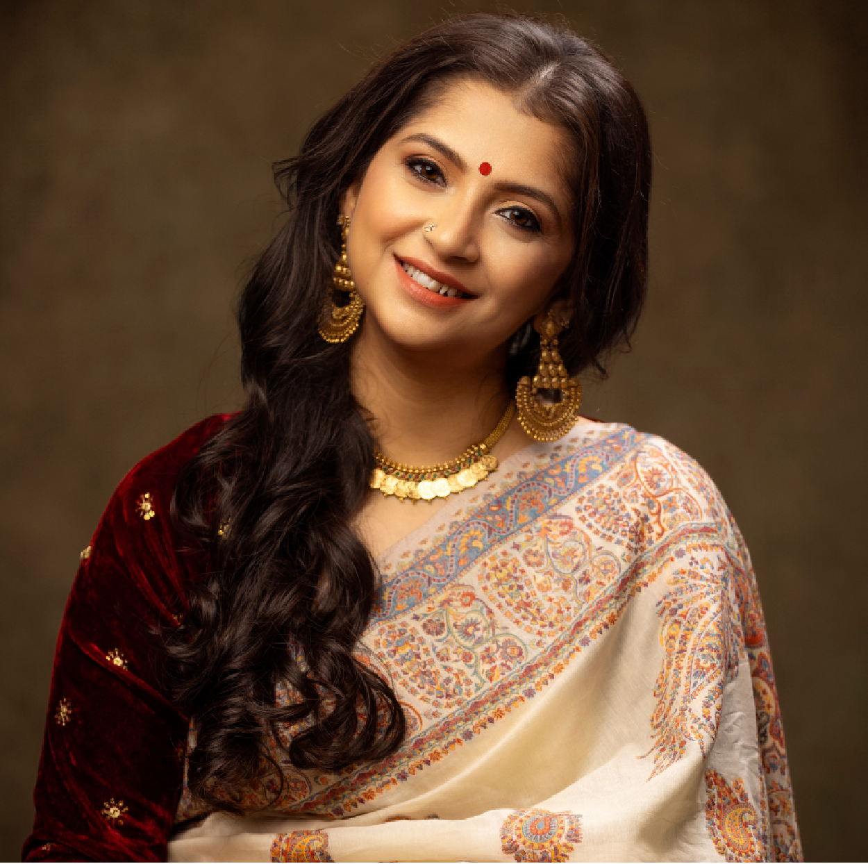 Indian classical vocalist Kaushiki Chakraborty performing on stage in a traditional saree, holding a tanpura.